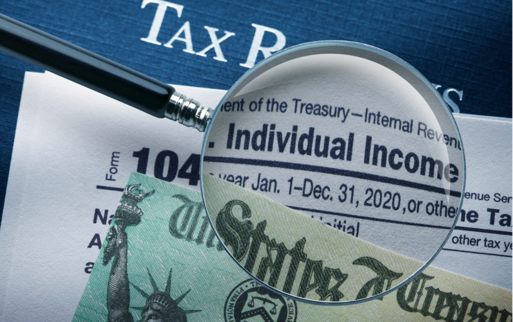 Magnifying glass examining Form 1040 Individual Income Tax Return with Treasury refund check visible in background, illustrating federal tax payments and refunds subject to paper check elimination
