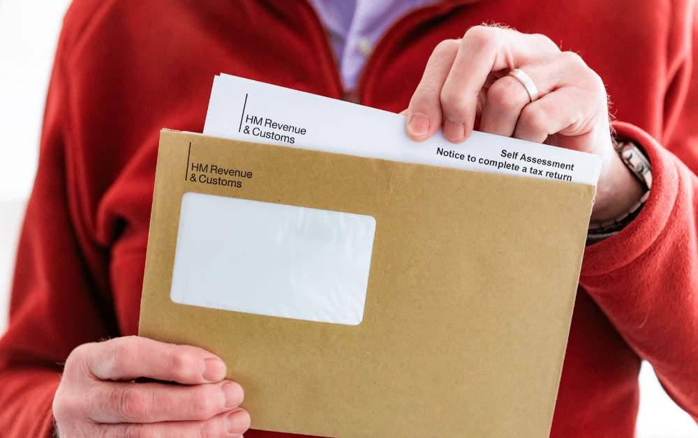 UK taxpayer holding brown HM Revenue & Customs envelope with Self Assessment notice to complete a tax return